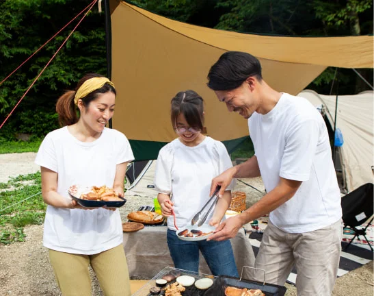 テントの前でバーベキューを楽しむ3人