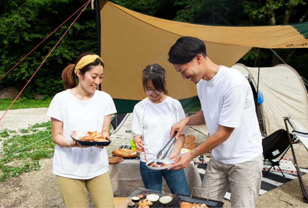 テントの前でバーベキューを楽しむ3人
