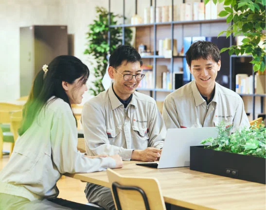 作業着姿でノートPCを囲む3人の社員