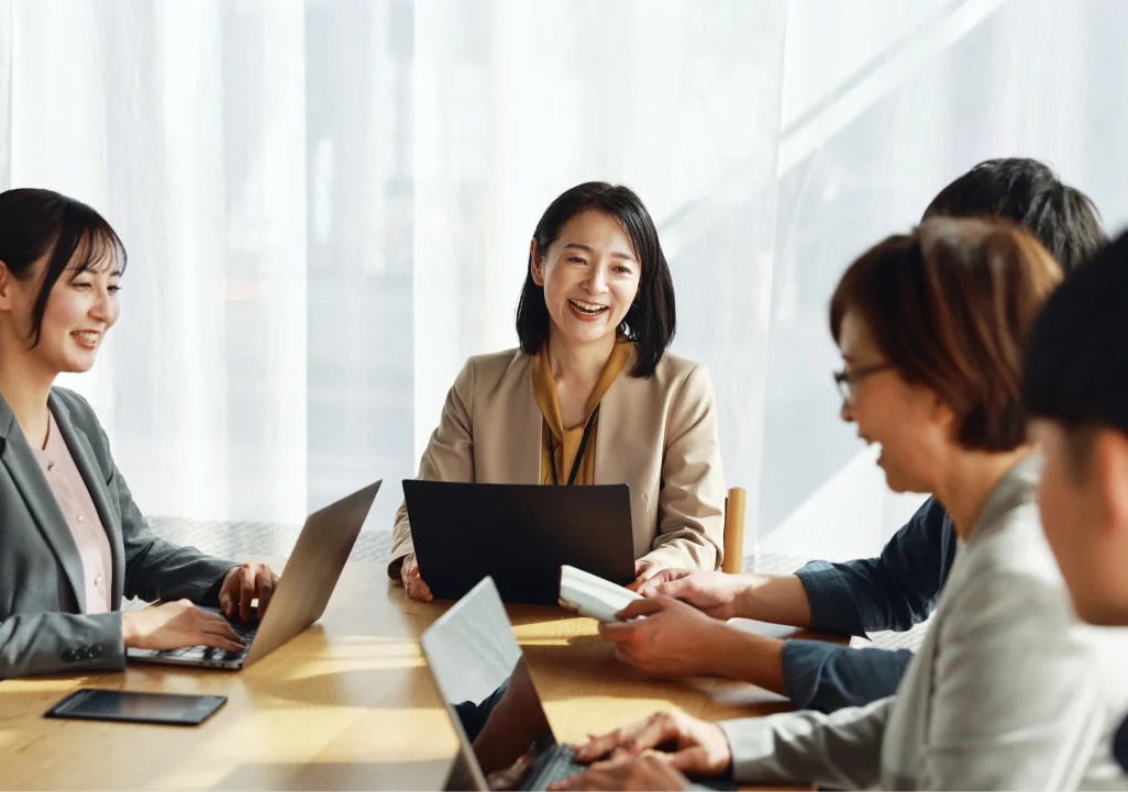 ノートPCを囲んで会議する社員たち