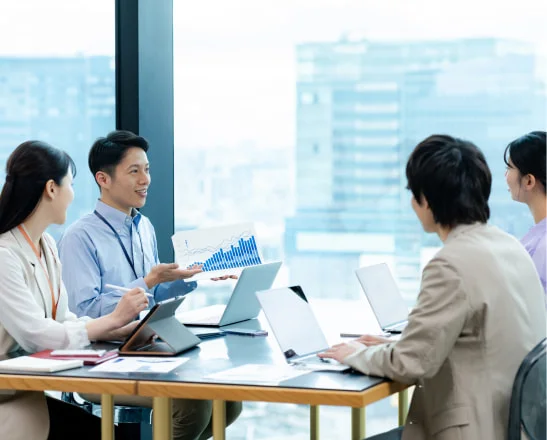 高層階でグラフ資料を示し話し合う社員