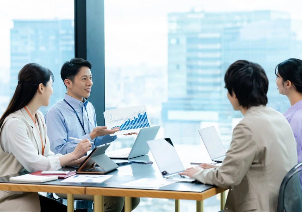 高層階でグラフ資料を示し話し合う社員