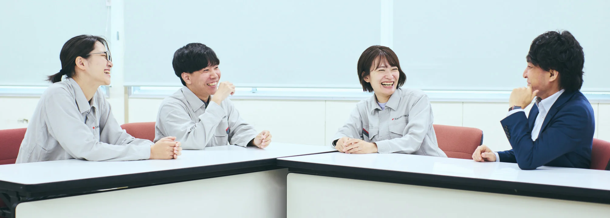 テーブルを囲んで笑い合う4人の社員