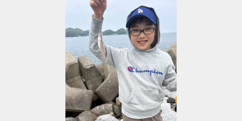 海辺で釣った魚を掲げる子ども
