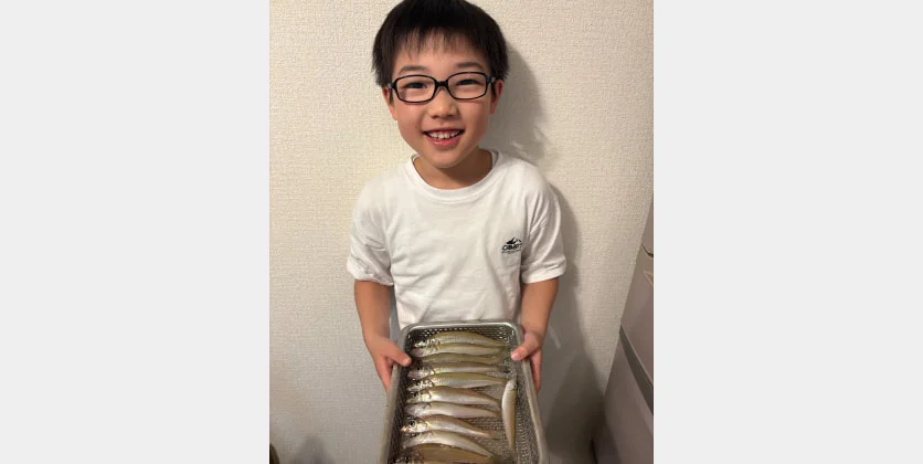 自宅で釣果の魚を手にする子ども