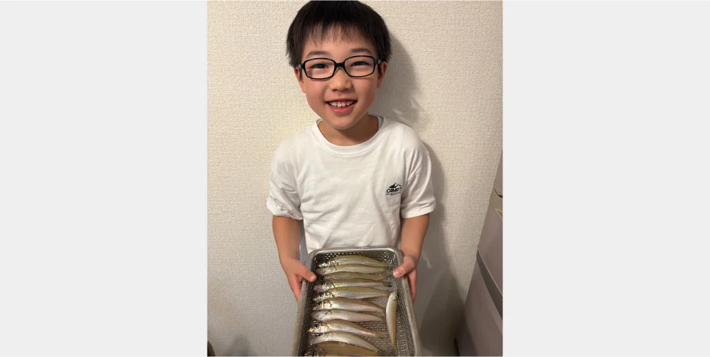 自宅で釣果の魚を手にする子ども