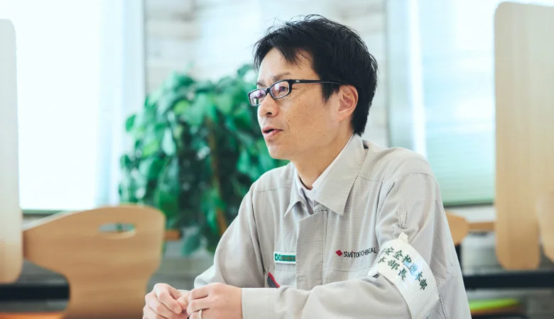 腕章をつけ室内で話すH. S.