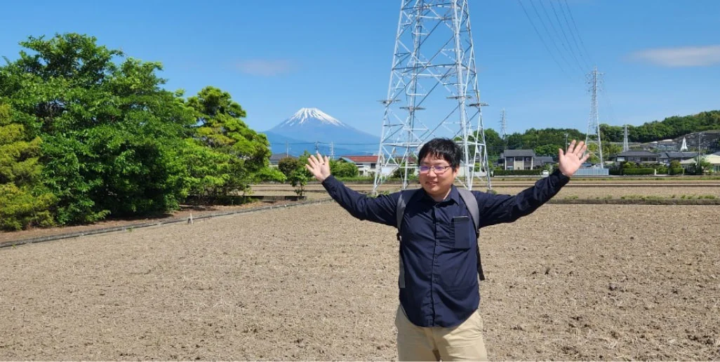 富士山を背にポーズを取るM. T.