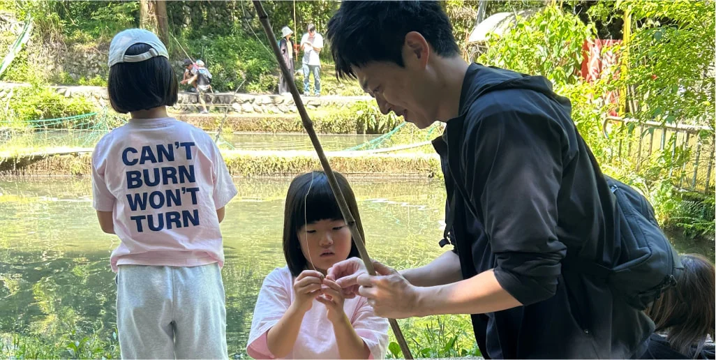 川辺で子どもと魚釣りをするF. H.